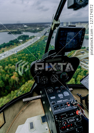 Cockpit view of Robinson R66 helicopter in flight above highway and forest 127174972