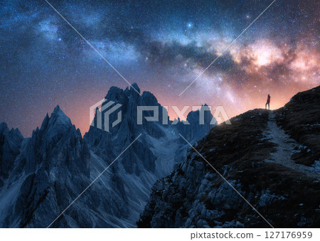 Glowing Milky Way and woman on mountain peak at starry night 127176959