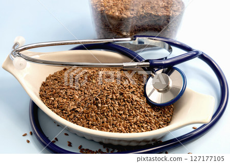 Healthy uncooked raw flax seeds and stethoscope Healthy uncooked raw flax seeds and stethoscope 127177105