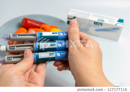 Hands holding Ozempic Insulin injection pen for diabetics and weight loss Hands holding Ozempic Insulin injection pen for diabetics and weight loss 127177118