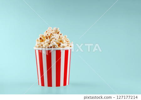 Classic red striped popcorn cardboard cup on blue background Classic red striped popcorn cardboard cup on blue background 127177214