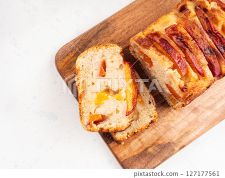 Peach cake loaf on wooden cutting board on white backgroud 127177561