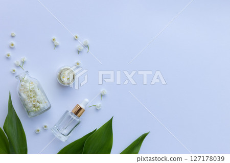 Glass bottle of lily of the valley essential oil with fresh flowers 127178039