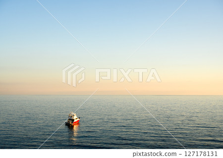 Evening coastal scene with lonely fishing boat Evening coastal scene with lonely fishing boat 127178131