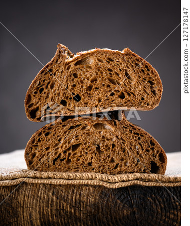 Two half of rye sourdough bread in section on a rustic wooden board Two half of rye sourdough bread in section on a rustic wooden board 127178147