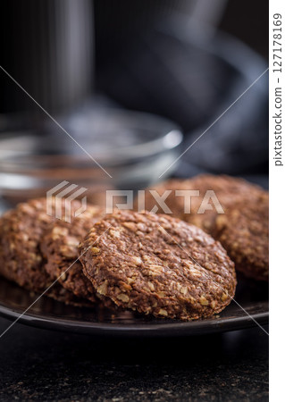 Sweet oatmeal cookies on plate on black table. 127178169