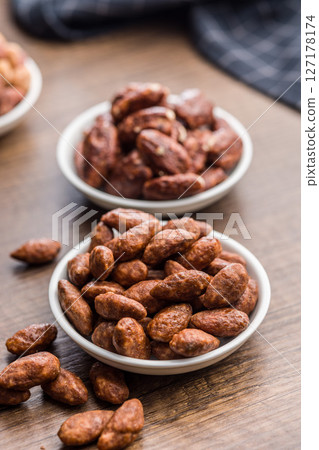 Almond nuts coated in sugar and honey in bowl on wooden table. Almond nuts coated in sugar and honey in bowl on wooden table. 127178174