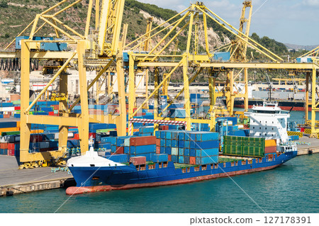 Cargo ship docked at container terminal with yellow cranes Cargo ship docked at container terminal with yellow cranes 127178391