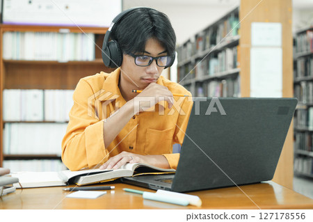 Young collage student using computer and mobile device studying online. 127178556