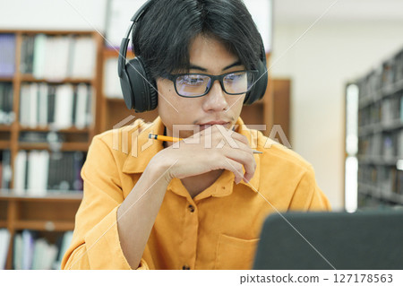 Young collage student using computer and mobile device studying online. Young collage student using computer and mobile device studying online. 127178563