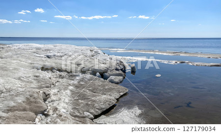 Blocks of melting ice on the shore of a vast lake during the spring thaw, Parnu, Estonia 127179034