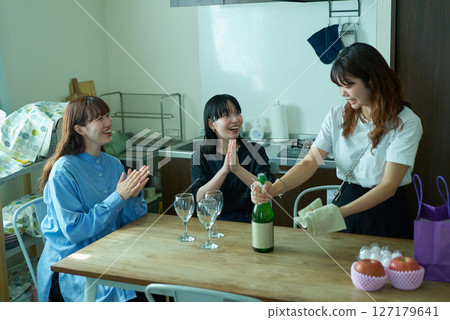 Women drinking wine at a home party 127179641