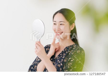 A woman looking at a mirror and smiling 127180547