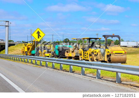 Heavy machinery is parked by highway for safe road construction in clear weather. 127182051