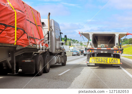 Large trucks carry oversized loads on crowded highway transportation in motion. Large trucks carry oversized loads on crowded highway transportation in motion. 127182053