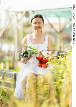 Adult woman with vegetable harvest in cottage garden Adult woman with vegetable harvest in cottage garden 127182902