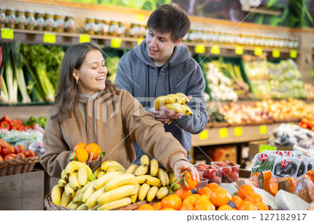 Young couple buying bananas and tangerines in grocery store Young couple buying bananas and tangerines in grocery store 127182917