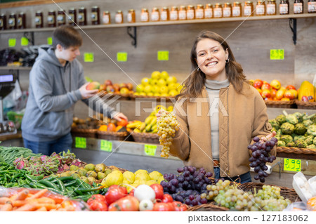 Girl purchaser choosing grape at the counter in grocery store 127183062