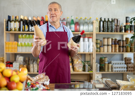 Mature salesman is offering wine in grocery store Mature salesman is offering wine in grocery store 127183095