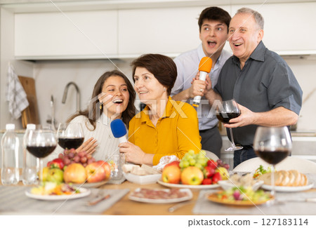 Friendly family with adult children singing karaoke together Friendly family with adult children singing karaoke together 127183114