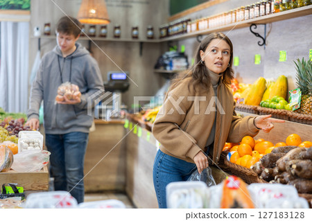 Young woman choosing tangerines in vegetable shop 127183128