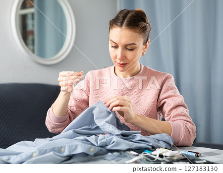 Woman repairing clothes with a needle and thread 127183130