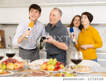 Joyful family singing at home karaoke during festive gathering 127183188