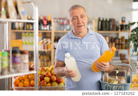 Mature man is choosing natural juice in grocery store Mature man is choosing natural juice in grocery store 127183202