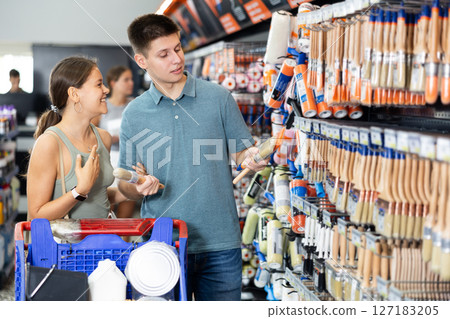 Young married couple buyer paint brushes together in hardware store Young married couple buyer paint brushes together in hardware store 127183205
