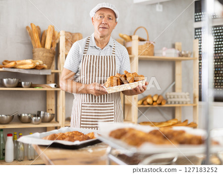 Elderly male baker with basket of croissants Elderly male baker with basket of croissants 127183252