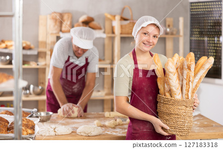 Smiling girl presenting freshly baked baguettes in family bakery Smiling girl presenting freshly baked baguettes in family bakery 127183318