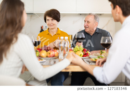 Father and mother together with adult children talking at dinner table at home Father and mother together with adult children talking at dinner table at home 127183346