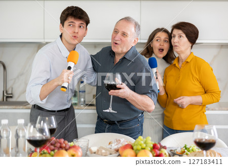 Cheerful multi-generational family singing into microphones at home party 127183411