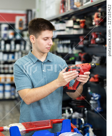 Man buys electric drill, collect necessary supplies in store according to list for apartment repairs Man buys electric drill, collect necessary supplies in store according to list for apartment repairs 127183422