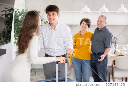 Cheerful young guy greeting wife returning home from trip 127183423