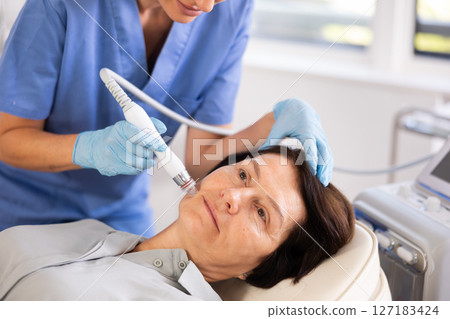 Aged woman undergoing cosmetic facial treatment using ion bubble attachment Aged woman undergoing cosmetic facial treatment using ion bubble attachment 127183424