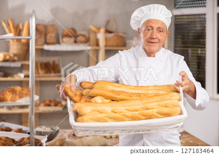 Elderly male seller showing assortment of bakery 127183464