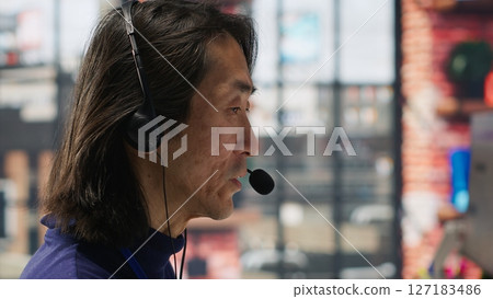 Closeup of senior call center agent helping customers regain access to accounts, resetting passwords. Experienced Asian worker in diverse customer center assisting clients needing help, camera A Closeup of senior call center agent helping customers regain access to accounts, resetting passwords. Experienced Asian worker in diverse customer center assisting clients needing help, camera A 127183486