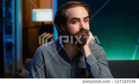 Man bored at home searching for TV series to binge on streaming services, procrastinating. Close up of person sitting on couch, flipping though TV channels using remote control, camera A 127183536