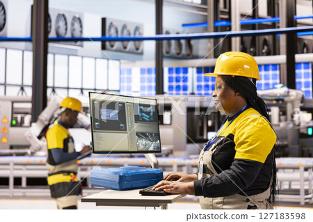 Automation engineer maintaining solar panel software in industrial facility. Professional female technician optimizing system performance and managing automated machinery in smart manufacturing plant. 127183598