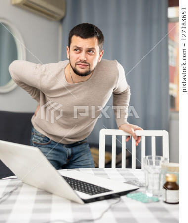 Man experiencing severe back pain after working long hours on laptop 127183651