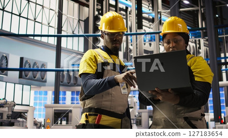 Engineering team doing brainstorming in smart factory, analyzing IoT sensor data. Industry 4.0 plant teamworking colleagues managing operational reliability of photovoltaic systems, camera A 127183654