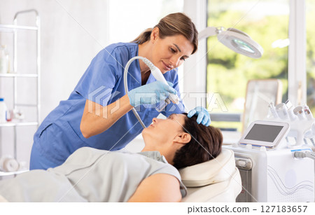 Female doctor doing cosmetology procedure for mature woman, RF lifting and deep hydration for facial skin therapy in clinic 127183657