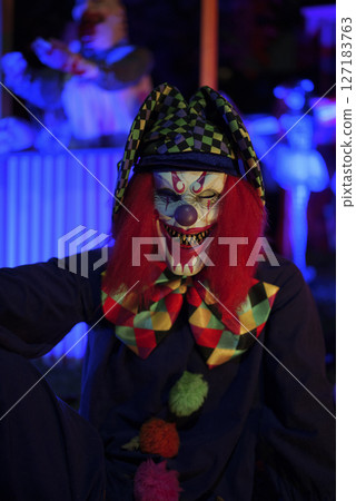 Evil Circus Clown in Scary Halloween Decor with Colorful Lights 127183763