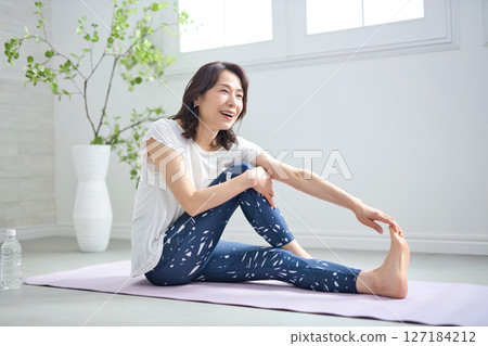 A woman in her 50s doing yoga in yoga wear 127184212