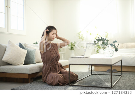 一位二十多歲的女子正盯著筆記型電腦，臉上帶著憂慮的表情 127184353