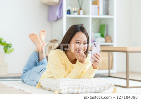 年輕女子在客廳看智慧型手機 年輕女子在客廳看智慧型手機 127184386