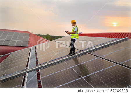 man in a yellow vest is walking on a roof with solar panels man in a yellow vest is walking on a roof with solar panels 127184503