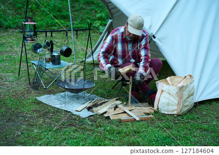 Solo camper splitting firewood, solo camping, senior 127184604