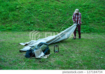 Solo camper setting up a tent, solo camping, senior Solo camper setting up a tent, solo camping, senior 127184734